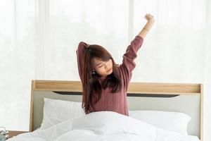 Aziatische vrouw op bed en 's ochtends wakker worden foto