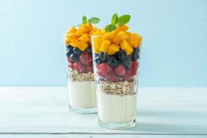 zelfgemaakte mango, framboos en bosbes met yoghurt en muesli - gezonde voedingsstijl foto