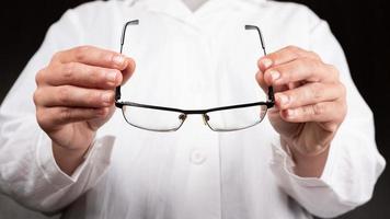opticien arts geeft een bril aan een patiënt om het gezichtsvermogen te verbeteren foto