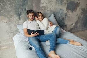 jong gelukkig glimlachen paar zittend Aan bed Bij huis foto