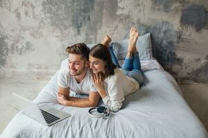 jong gelukkig glimlachen paar zittend Aan bed Bij huis foto