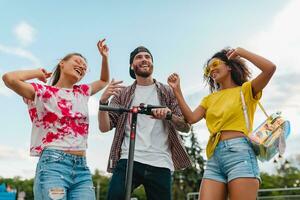 gelukkig jong bedrijf van glimlachen vrienden dansen wandelen in straat met elektrisch trap scooter foto