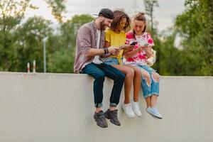 gelukkig jong bedrijf van glimlachen vrienden zittend in park foto