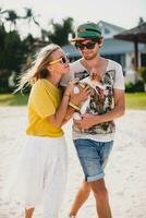 koel jong elegant hipster paar in liefde wandelen spelen hond puppy jack Russell in tropisch strand, wit zand, romantisch stemming, hebben plezier, zonnig, Mens vrouw samen, vakantie foto