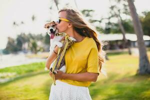 jong elegant hipster vrouw Holding wandelen spelen hond puppy jack Russell foto