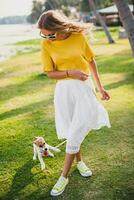 jong elegant hipster vrouw Holding wandelen spelen hond puppy jack Russell foto