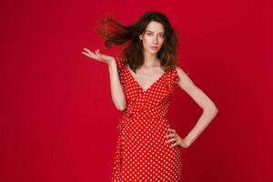 elegant vrouw in zomer mode neiging jurk Aan rood achtergrond foto