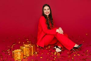 aantrekkelijk vrouw vieren Kerstmis Aan rood achtergrond in confetti foto