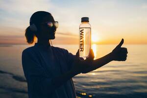 vrouw Bij zee Holding fles van water foto