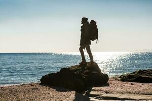 jong hipster Mens op reis met rugzak in verkoudheid seizoen door de zee foto