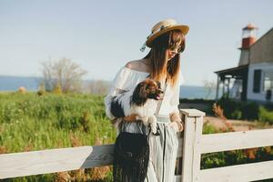 visie van terug Aan elegant vrouw in platteland, Holding een hond foto