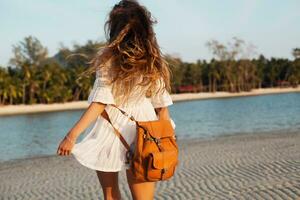 slank mooi vrouw in wit katoen jurk wandelen Aan tropisch strand foto