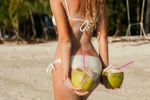 jong mager vrouw in wit bikini badmode Holding kokosnoten foto