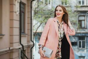 schattig jong mooi elegant vrouw wandelen in straat in roze jas foto