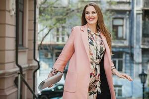 portret van aantrekkelijk elegant glimlachen vrouw wandelen stad straat in roze jas foto