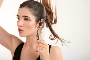aantrekkelijk vrouw in jogging zwart top luisteren naar muziek- Aan oortelefoons foto