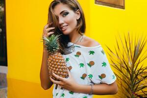 aantrekkelijk glimlachen vrouw Aan vakantie Holding ananas foto