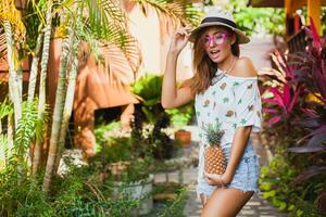 aantrekkelijk glimlachen vrouw Aan vakantie Holding ananas foto