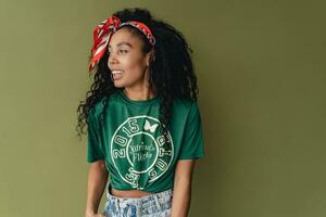 aantrekkelijk zwart Afrikaanse Amerikaans vrouw poseren in elegant hipster kleding Aan groen achtergrond foto