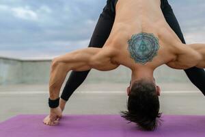 aantrekkelijk knap Mens met atletisch sterk lichaam aan het doen ochtend- yoga asana buitenshuis foto