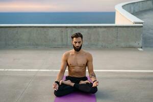 aantrekkelijk knap Mens met atletisch sterk lichaam aan het doen ochtend- yoga dzen meditatie foto