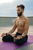 aantrekkelijk knap Mens met atletisch sterk lichaam aan het doen ochtend- yoga dzen meditatie foto