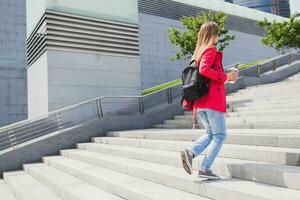 jong hipster vrouw in roze jas, jeans in straat foto