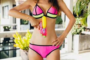 mooi slank vrouw spelen met waterpistool speelgoed- Bij zwembad Aan zomer tropisch vakantie foto