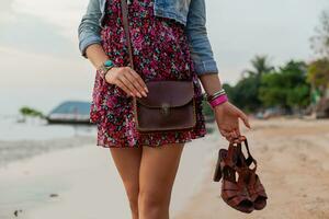 elegant vrouw in zomer jurk vakantie wandelen Aan strand met schoenen in hand- foto