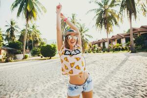 aantrekkelijk hipster vrouw zittend Aan strand luisteren naar muziek- Aan hoofdtelefoons foto