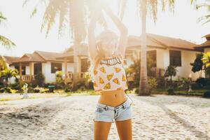 aantrekkelijk hipster vrouw zittend Aan strand luisteren naar muziek- Aan hoofdtelefoons foto