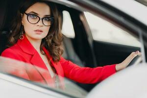 mooi sexy rijk bedrijf vrouw in rood pak zittend in wit auto, vervelend bril foto