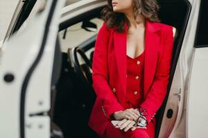 mooi sexy rijk bedrijf vrouw in rood pak poseren in wit auto foto