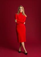 elegant blond vrouw in rood herfst winter mode jurk poseren geïsoleerd vol hoogte Aan rood studio achtergrond foto