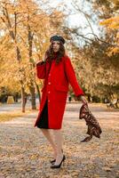 aantrekkelijk elegant vrouw wandelen in park gekleed in warm rood jas foto