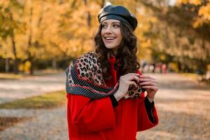 aantrekkelijk elegant vrouw wandelen in park gekleed in warm rood jas foto