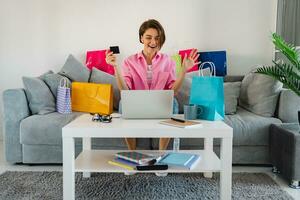 gelukkig glimlachen vrouw in roze overhemd Aan sofa Bij huis boodschappen doen online foto