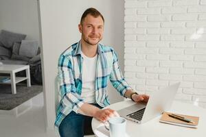 Mens in overhemd zittend in keuken Bij huis Bij tafel werken online Aan laptop foto