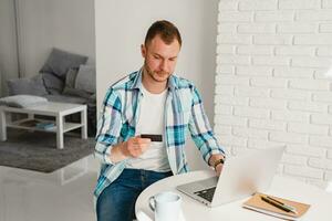 Mens in overhemd zittend in keuken Bij huis Bij tafel werken online Aan laptop foto