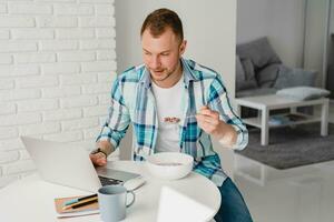 Mens in overhemd zittend in keuken Bij huis Bij tafel werken online Aan laptop foto