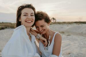 twee jong Dames hebben pret Aan de zonsondergang strand foto