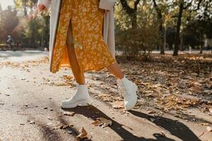 detailopname poten in elegant wit laarzen schoenen van jong vrouw in geel gedrukt jurk foto