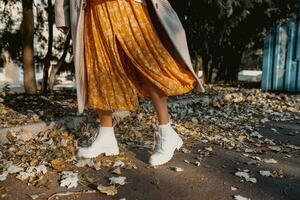 detailopname poten in elegant wit laarzen schoenen van jong vrouw in geel gedrukt jurk foto