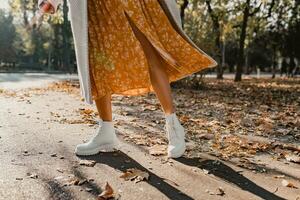 detailopname poten in elegant wit laarzen schoenen van jong vrouw in geel gedrukt jurk foto