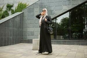 modern elegant moslim vrouw in hijab in stad straat foto