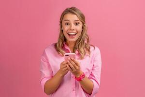 blond mooi vrouw in roze overhemd glimlachen Holding Holding gebruik makend van smartphone foto