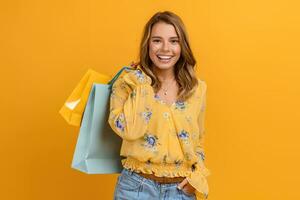 mooi aantrekkelijk glimlachen vrouw in geel overhemd en jeans Holding boodschappen doen Tassen foto