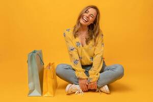 mooi aantrekkelijk glimlachen vrouw in geel overhemd en jeans met boodschappen doen Tassen foto