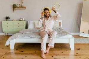 glimlachen vrouw ontspannende Bij huis Aan bed in ochtend- in pyjama luisteren naar muziek- foto