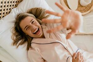 mooi glimlachen vrouw ontspannende Bij huis Aan bed in ochtend- in pyjama foto